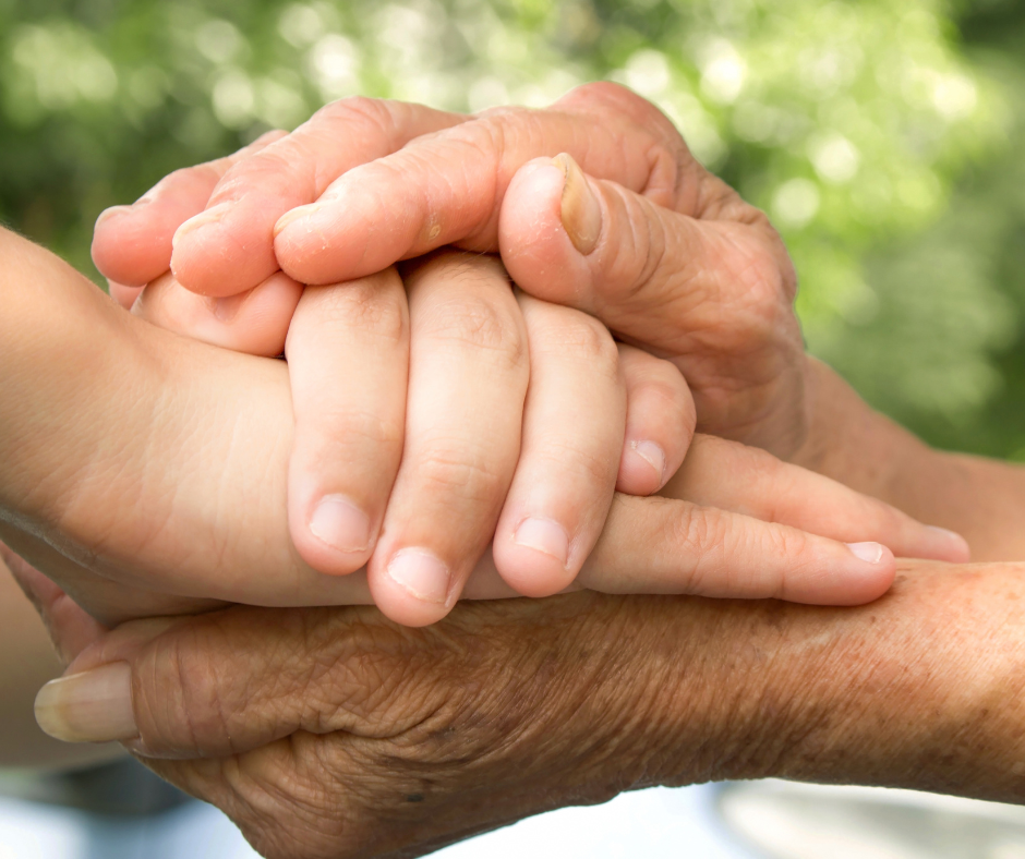 One pair of older hands holding a child's two hands